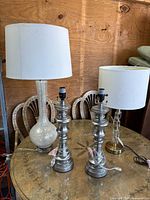 Four lamps grouped: frosted glass with shade, acrylic with shade, and pair of silver lamps without shades
