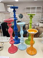 Five colorful enamel metal candle holders standing on tabletop