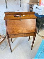 Closed oak child’s drop-front desk with spectacles and case resting on top