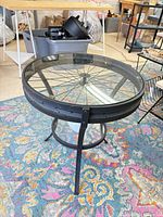 Full view of side table showing glass top, wheel spokes and legs
