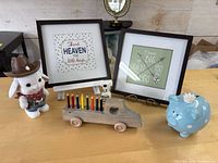 Group shot of both framed prints, bunny figurine, wooden truck with pencils, blue piggy bank