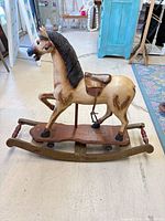 Full side view of carved wooden rocking horse on curved rocker base