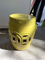 Full view of yellow ceramic garden stool showing cutouts and studded rim