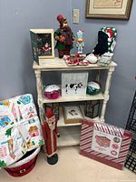 Overall view of shelf containing blankets, figurines, ornaments, artwork, stocking, bucket and sign