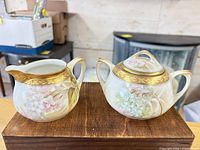 Creamer and sugar bowl front view showing floral design and gold trim
