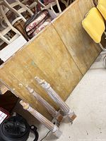 table top panels and four turned legs leaning against wall