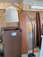 Entire floor lamp showing arched black metal stand and rattan dome shade