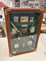 Front view of golf memorabilia shadowbox with miniature clubs, balls, medallion and prints