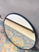 Front view of round mirror with navy frame on floor