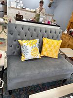 Full view of gray-blue tufted loveseat against wall