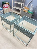 Two light aqua metal nesting tables with glass tops