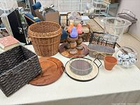 Full lot overview on tabletop showing baskets, chargers, candlesticks, trays, vase, container, pot and books