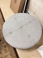 Top view of gray round tufted ottoman showing four button tufts