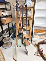 Full view of coat rack showing three oars, metal hooks, umbrella ring