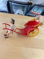Side view of red plastic rickshaw and puller figure