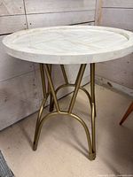 Overall view of round side table with stone tile top and gold metal legs