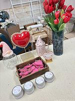 Full lot view showing tulip vase, light-up heart, mug with lid, XOXO plaque, wood crate with ornaments, four candle tins and candy jar