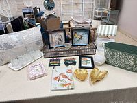 Full lot overview on table showing pillow, glass holders, wall art, trays, planter, shelf