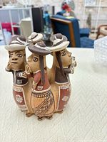 Front view of terracotta circle of six women sculpture showcasing detailed painting and whistle openings