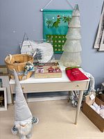 Tabletop view showing glass tree, sweater kit box, garland game box, wings, basket, advent calendar, plush gnome