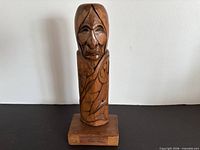 Full view of carved wooden totem on base