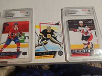 Three hockey rookie cards, two graded slabs and one raw