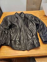 Front view of black leather coat laid flat showing overall style and condition