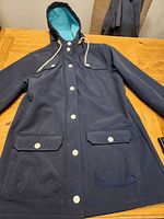 Front view Lily Morgan navy blue hooded jacket with aqua lining and anchor snap buttons