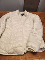 Front view of cream quilted puffer jacket laid flat
