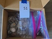 Three resealable bags of coins inside open cardboard box