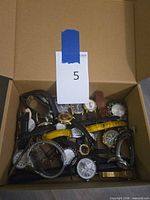 Box containing pile of assorted wristwatches