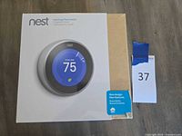 Front of Nest Learning Thermostat retail box showing product image and serial number noted