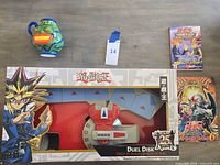 Group shot showing Duel Disk in box, Pot of Greed mug, and two Japanese books