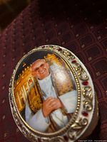 Lidded porcelain music box top showing portrait, gold and red detailing