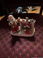 Front view of ceramic Santa and fireplace figurine on chair