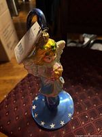 Glass angel topper on blue swirl stand, tag visible