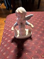 Front view of seated child angel porcelain figurine