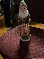 Front view of resin Santa figurine showing gold-bronze robe, white beard, black gloves