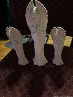 Front view of three porcelain praying angel figurines displayed on chair