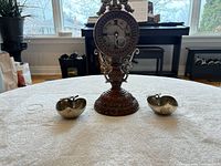 Front view of clock and two apple dishes on table