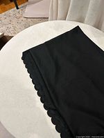 Folded black tablecloth placed on surface showing scalloped lace edge detail