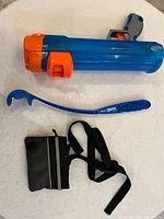 Nerf blue and orange plastic ball cannon, Chuckit blue ball thrower, black-gray treat pouch with strap