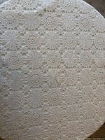 Close-up of spread-out crocheted cotton tablecloth showing motif and color