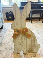 Front view of distressed white wooden bunny with burlap bow