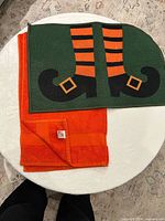 Rug with witch legs design and orange towel laid flat showing full coloration and texture