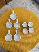 Overhead view of 6 handled bowls and 7 ramekins displayed on table