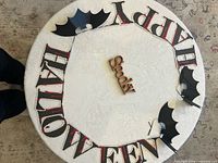 Overall view of letter banner pieces arranged in a circle, wooden “Spooky” sign at center, bat cutouts around edge