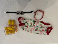 Group shot of all four items: holiday dog shirt, orange collar, black rhinestone bow collar, container with yellow pieces