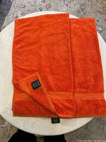 Both orange bath towels folded showing size, trim band and Lauren Ralph Lauren label