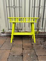 Front view of lime green wooden plant stand showing spindle sides and lower shelf